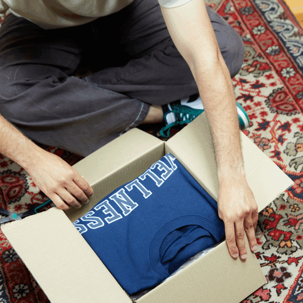 How to start your own clothing brand with no experience using POD A man is taking out a hoodie from a delivery box.