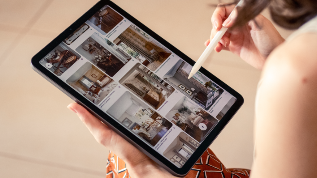 Step 5 What pin formats and designs work best for Etsy products A woman holds a tablet displaying a photo of a house, smiling as she looks at the screen.